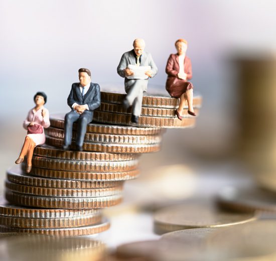 Kleine Figuren sitzen auf einem Stapel Münzen, der sehr wackelig aussieht. Symbolbild für die Inflation.