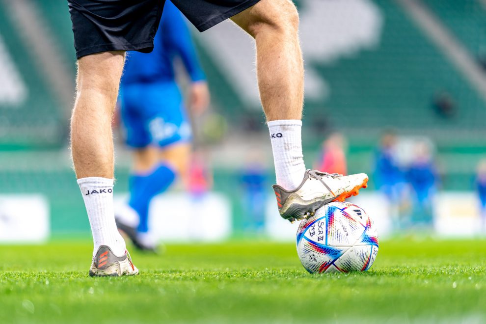 Ein Fußballspieler steht mit dem rechten Bein auf einem Fußball. Symbolbild für den Kollektivvertrag im Fußball und Zurück ins Spiel.