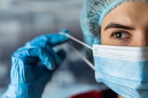 Eine Frau, die in der Pflege arbeitet, zieht sich eine Maske ab.