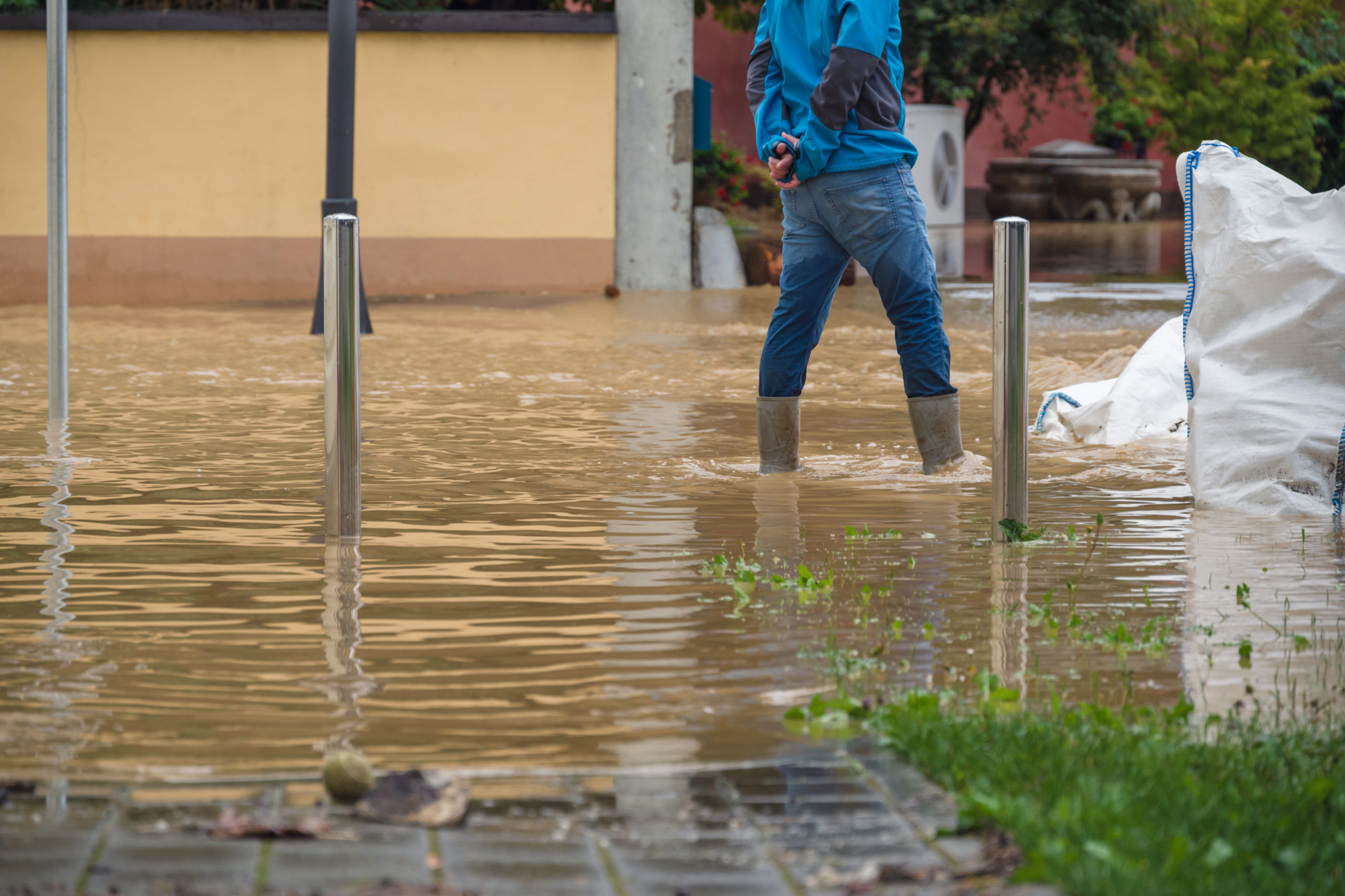 Ein Mann in Gummistiefeln geht durch eine überschwemmte Straße. Symbolbild für den Klimawandel.
