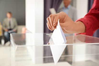 Eine Person wirft einen Stimmzettel in eine Wahlurne. Symbolbild für die AK Wahlen.