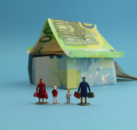 Haus aus Geldscheinen mit einer Familie im Vordergrund. Symbolbild für den gemeinnützigen Wohnbau.