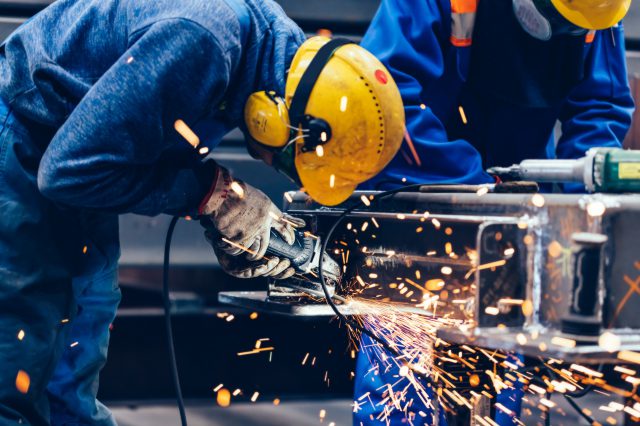 Arbeiter:innen arbeiten in einer Fabrik. Symbolbild für Wirtschaftspolitik.