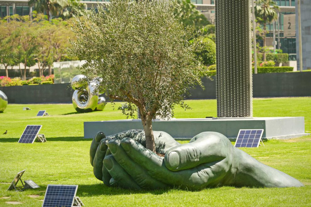 Hände halten Baumskulptur. Symbol der Erhaltung und Schutz der Natur im Rahmen der COP28 in Dubai.