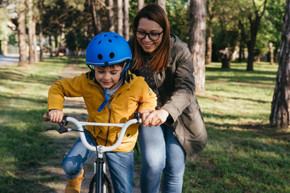 Eine Mutter hilft ihrem Sohn Fahrradfahren zu lernen. Symbolbild für den Sozialstaat stärken.