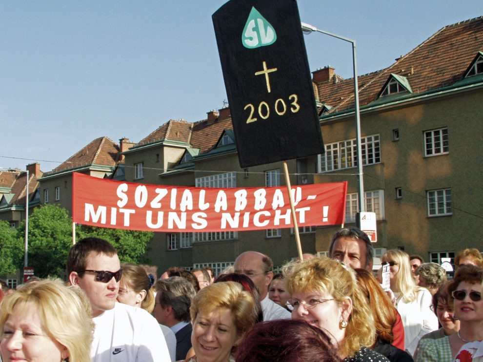 Eine Demo im Jahr 2003. Es ist eine Menschenmenge zu sehen, die Schilder mit der Aufschrift "Sozialabbau - mit uns nicht!" und "SVS, Kreuzzeichen, 2003" tragen. Symbolbild für den Leistungsabbau in der Sozialversicherung.