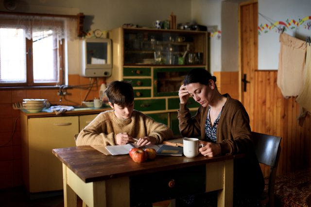 Ein alleinerziehende Mutter sitzt mit ihrem Sohn an einem Esstisch. Sie lebt in Armut in Österreich.