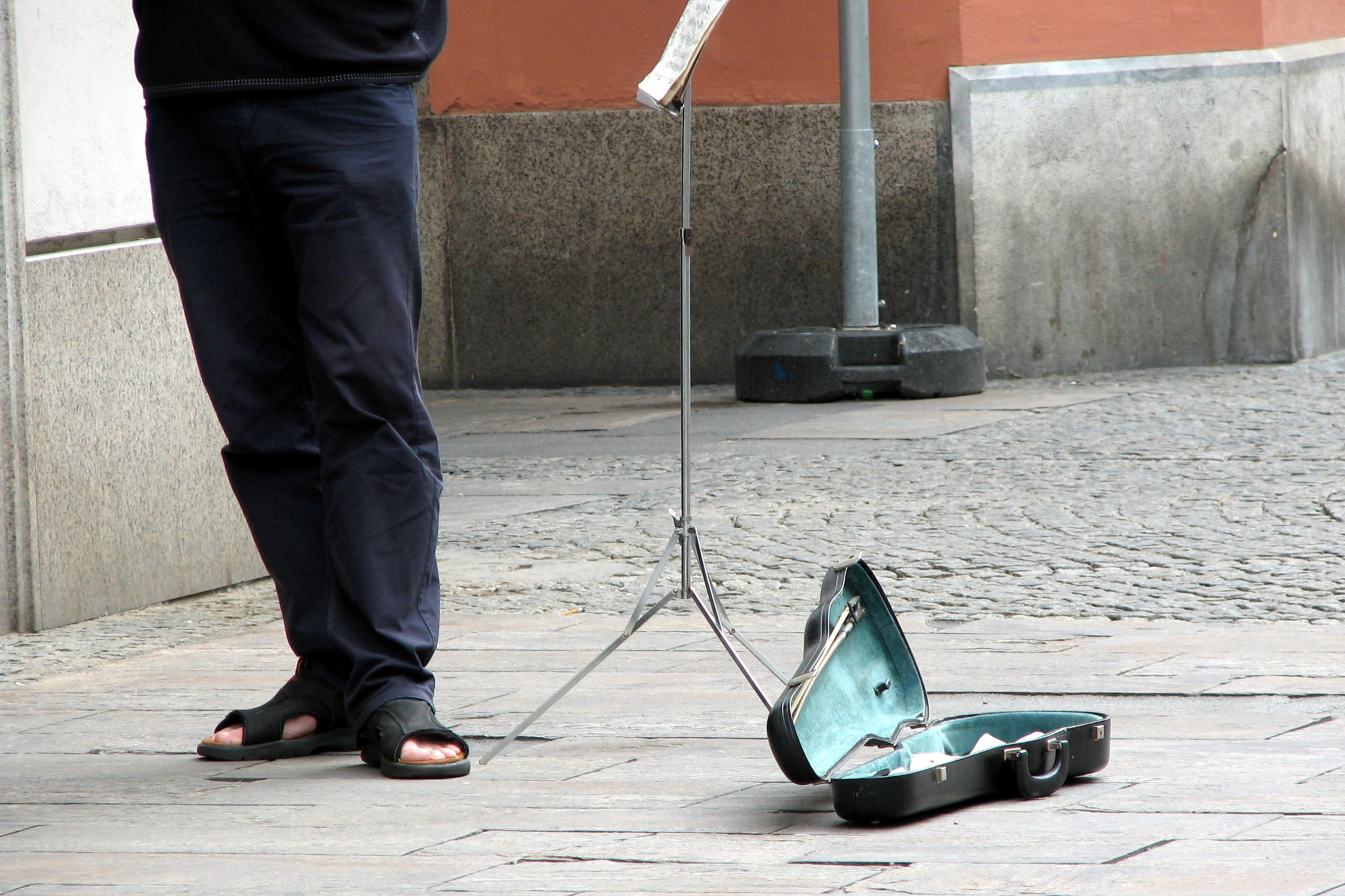 Ein Straßenmusiker sammelt Kleingeld in einem Geigenkoffer. Er kämpft gegen Armut in Österreich.