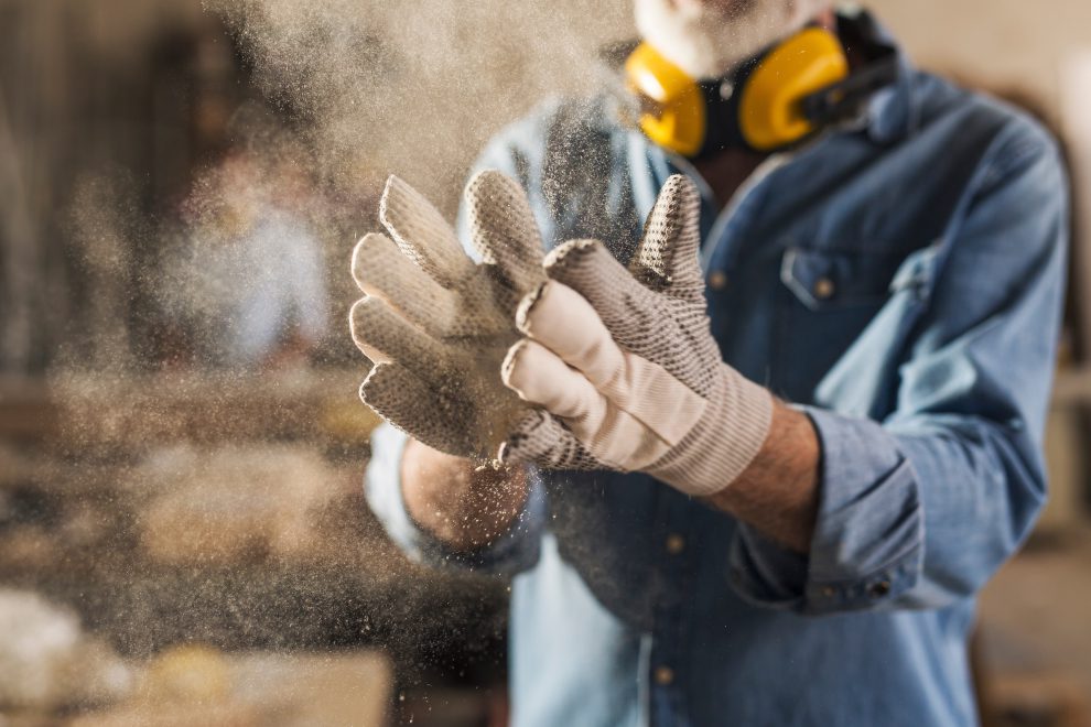 Ein Arbeiter schlägt sich in die Hände. Er trägt Arbeitshandschuhe und Lärmschutzkopfhörer. Symbolbild für eine Europäische Jobgarantie.