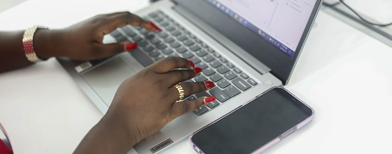 Hände einer Schwarzen Frau. Sie schreibt auf einer Tastatur.