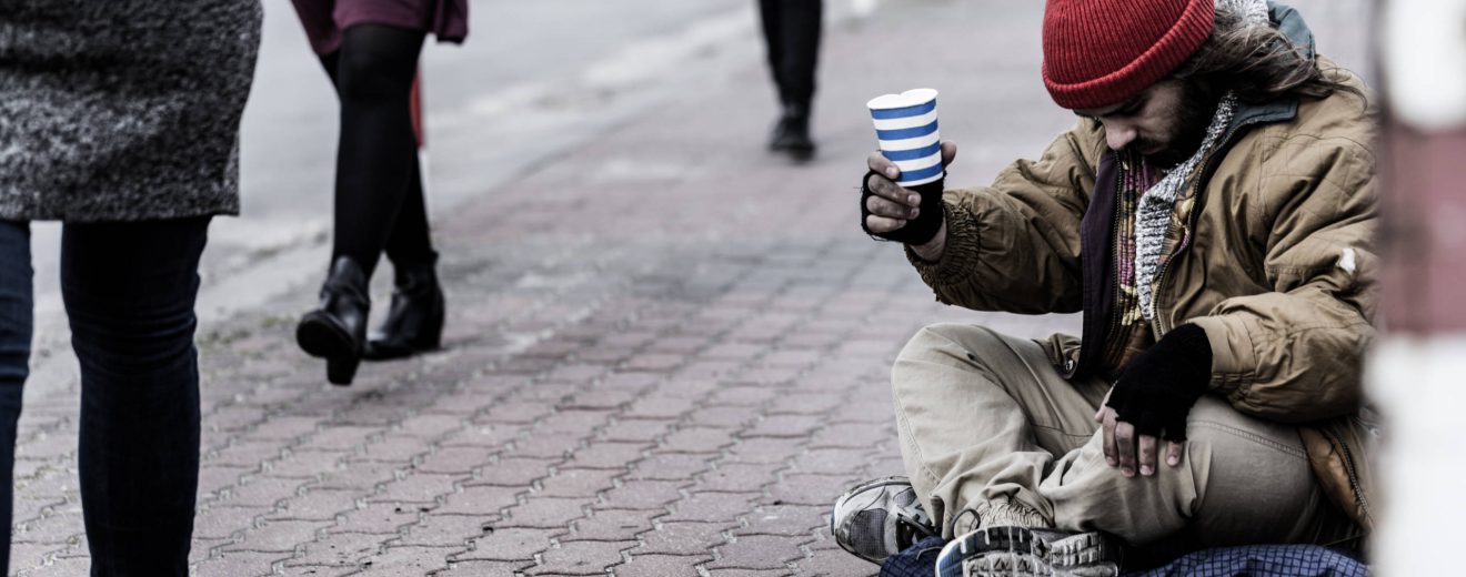 Ein obdachloser Mensch bettelt in der Straße um Geld.