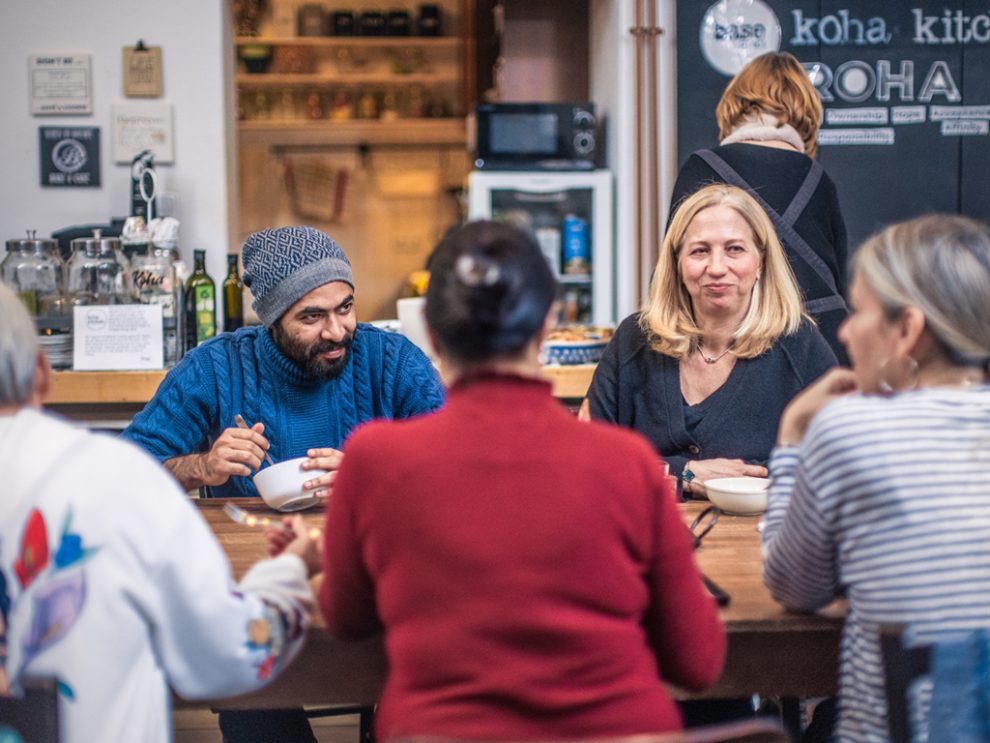 Menschen sitzen um einen Tisch und essen. Symbolbild für den Migrant:innenbeirat in Graz.