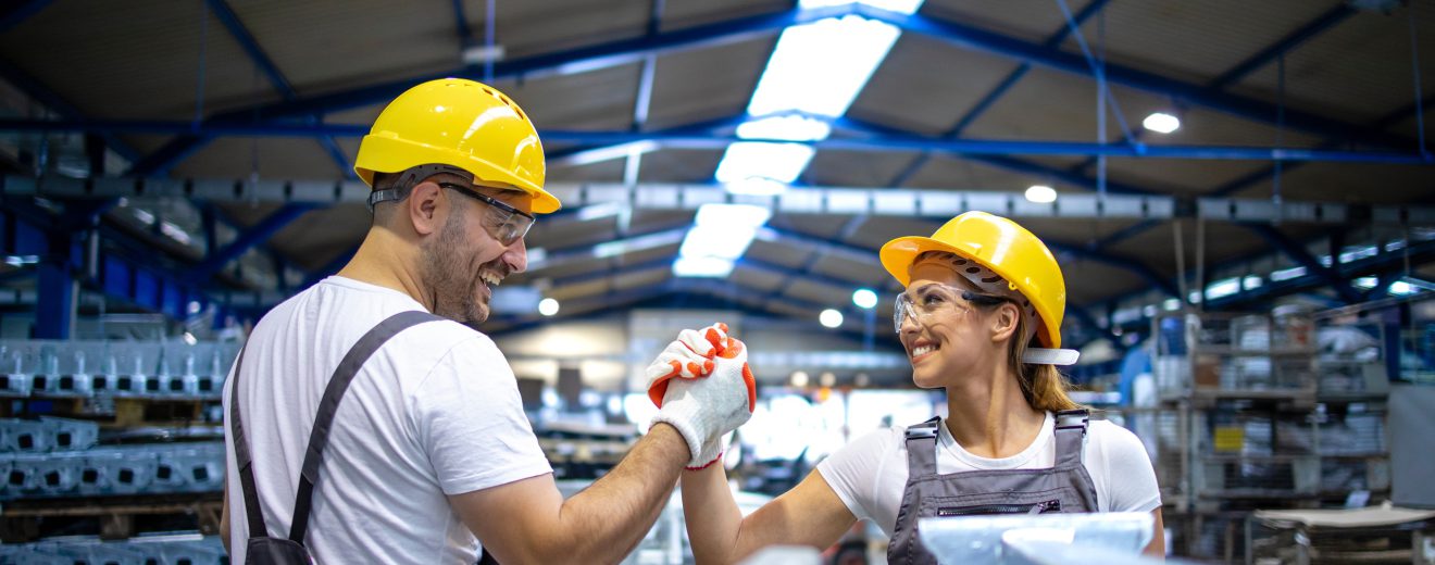 Zwei Arbeiter:innen in einer Fabrik schlagen ein. Symbolbild für 80 Jahre ÖGB.