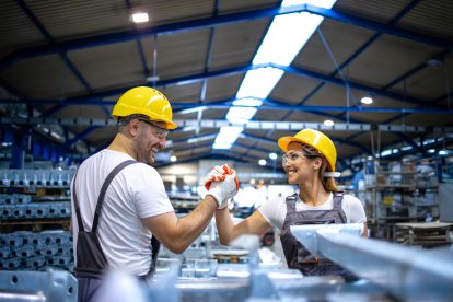 Zwei Arbeiter:innen in einer Fabrik schlagen ein. Symbolbild für 80 Jahre ÖGB.