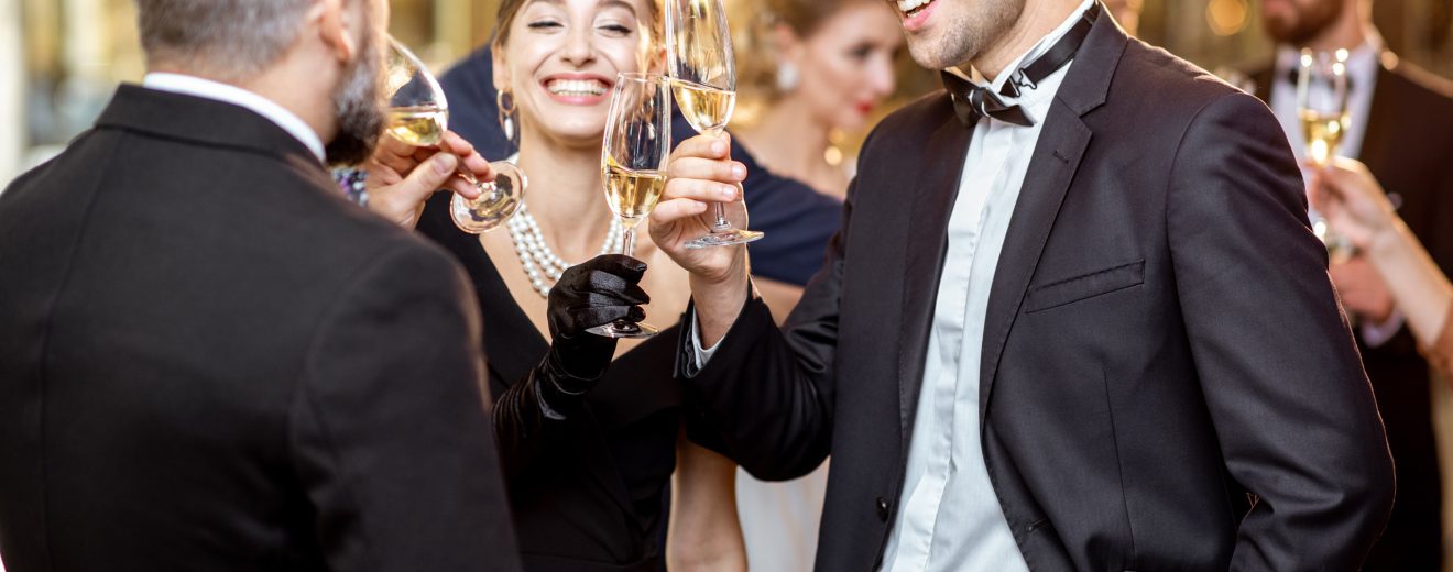 Menschen in Abendkleidung prosten sich mit Champagnergläsern zu. Symbolbild für Superreiche.