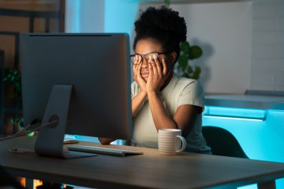 Überarbeitete Frau reibt sich die Augen. Symbolbild für unbezahlte Überstunden.