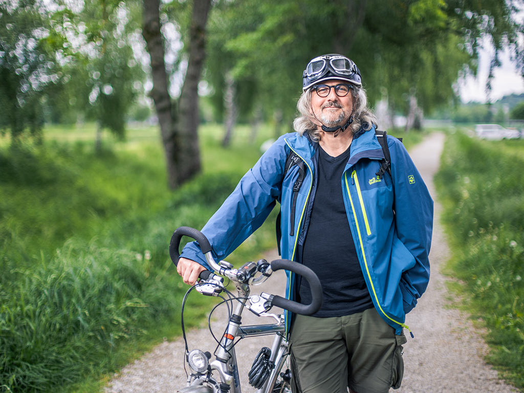 Lothaer Hasenleithner hat einen Fahrradhelm auf und steht neben einem Fahrrad auf einem Feldweg.