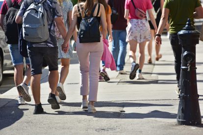 Menschen laufen auf der Straße, zwei halten sich an den Händen. Symbolbild für den Sozialstaat in Österreich. | © Adobe Stock/Spitzi-Foto