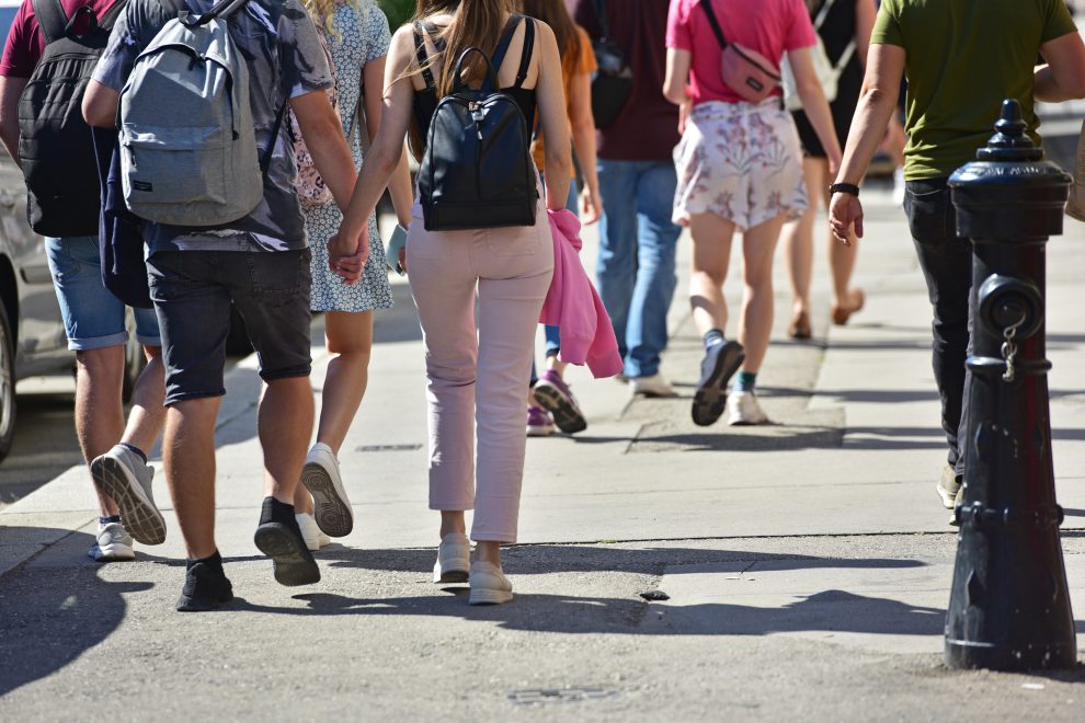 Menschen laufen auf der Straße, zwei halten sich an den Händen. Symbolbild für den Sozialstaat in Österreich. | © Adobe Stock/Spitzi-Foto