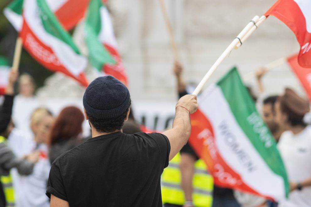 Menschen wehen iranische Flaggen bei einem Protest.