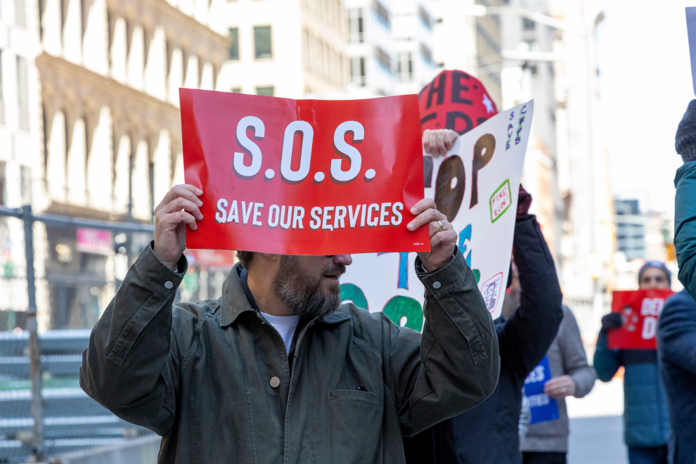 Ein Protestant hält ein Schild in die Höhe mit dem Schriftzug "Save our Services". Symboldbild für den Druck auf die Gewerkschaften in den USA. | © Gina M Randazzo / Zuma / picturedesk.com