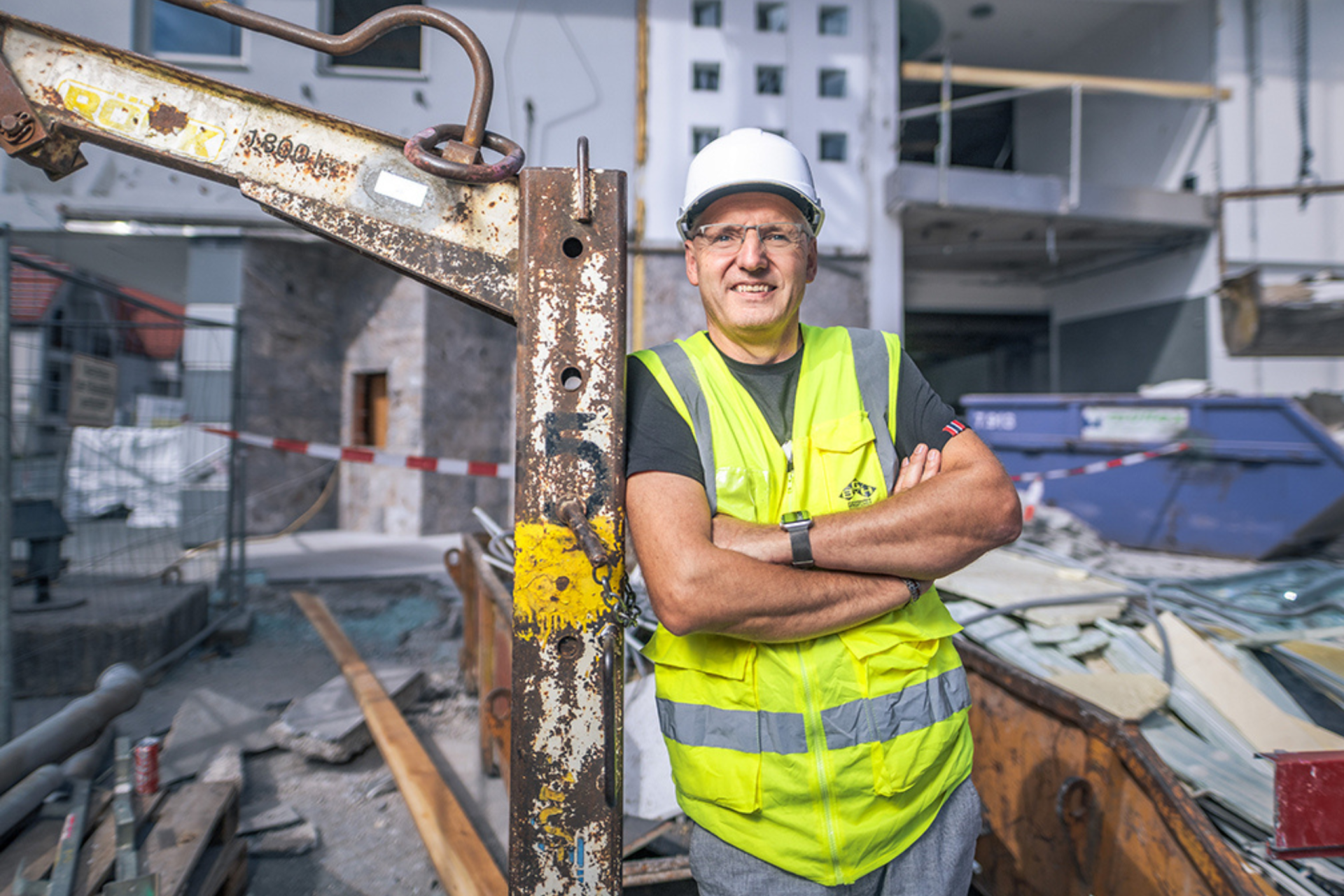 Andreas Linke steht mit Bauhelm und Sicherheitsweste auf einer Baustelle. Symbolbild für Menschen aus dem Ausland, die in Österreich arbeiten.