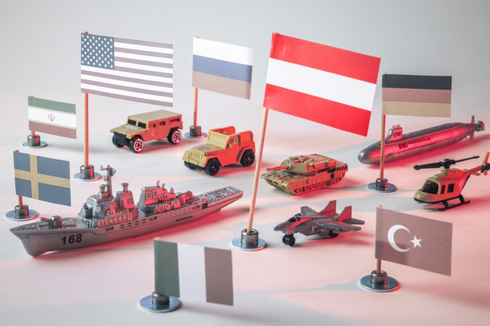 Kriegsfahrzeuge mit Flaggen aus der Welt. Symbolbild für die globale Aufrüstung und die Auswirkungen auf Österreich.