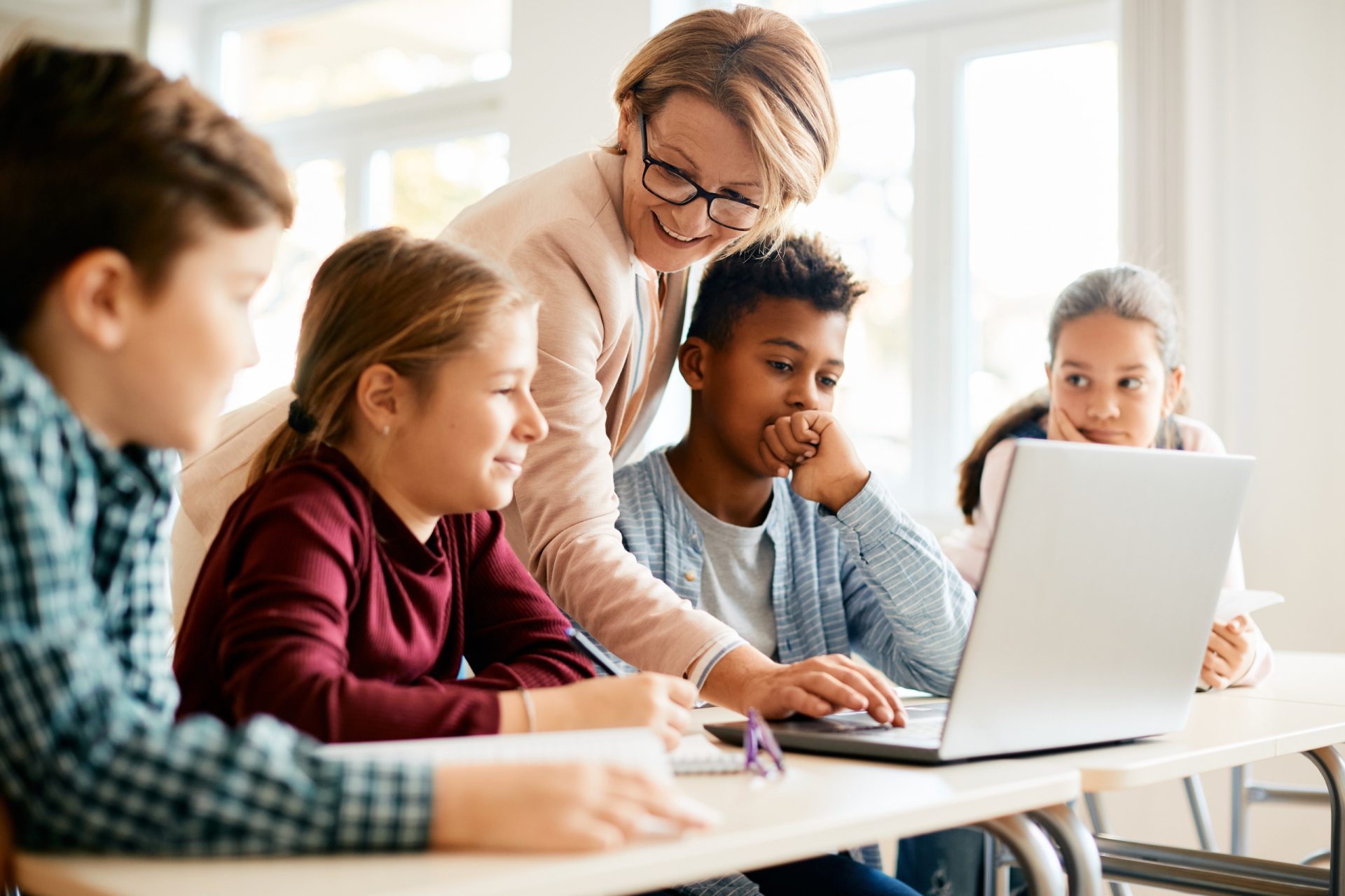 Eine Lehrerin arbeitet mit einer Gruppe Kinder. Symbolbild für Verhandlungen der Beamtengewerkschaft. 