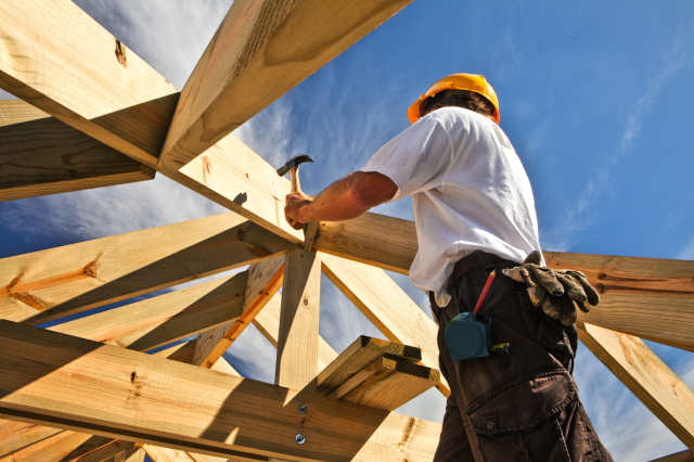Ein Bauarbeiter arbeitet an einem Holzgebäude. Symbolbild für die Ausbeutung in der österreichischen Baubranche.