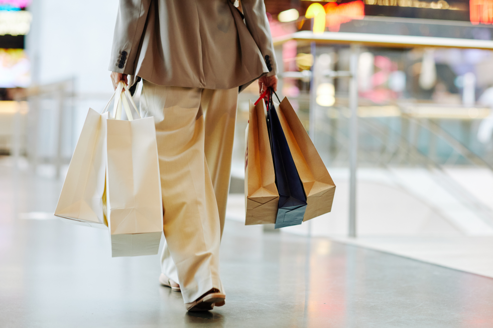 Eine Person trägt Einkaufstaschen durch ein Shopping Center. Symbolbild für: Lohneinsparungen haben schwerwiegende indirekte Folgen.