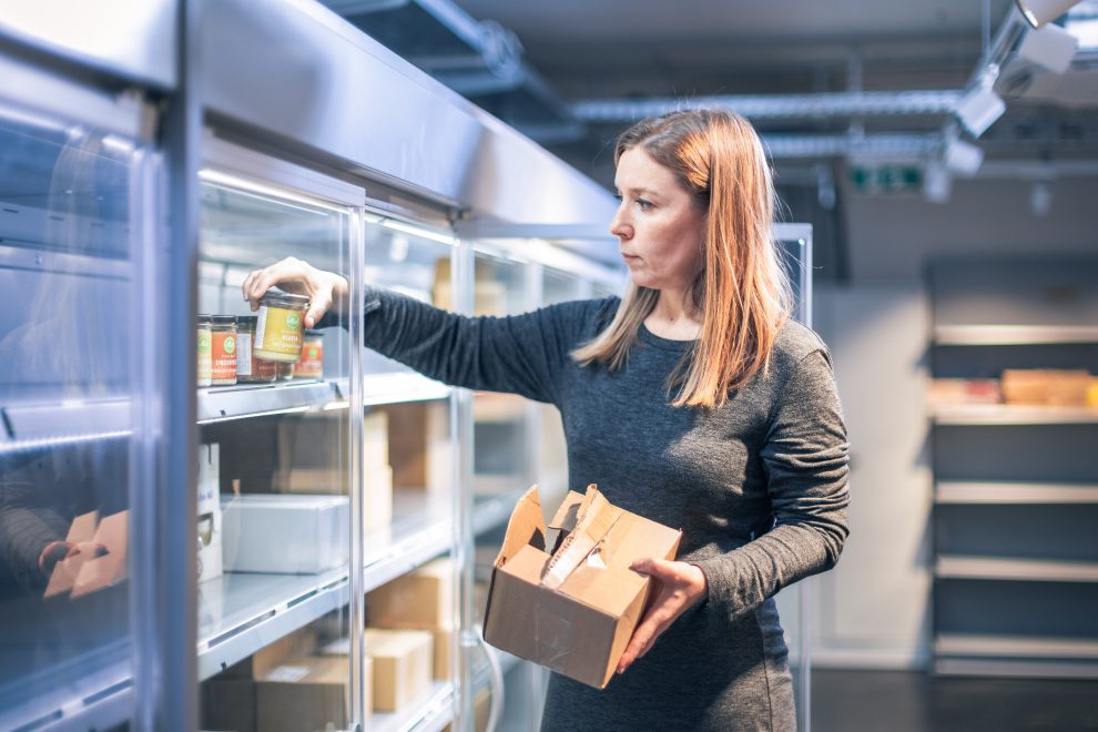 Eine Frau räumt im Supermarkt ein Regal ein. Symbolbild für den Mitmachsupermarkt MILA.