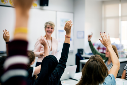 Eine ältere Lehrerin steht vor der Klasse. Symbolbild für den Kompromiss bei den Gehältern, den die Beamt:innen jetzt aufgrund des Budgetlochs abgeschlossen haben.
