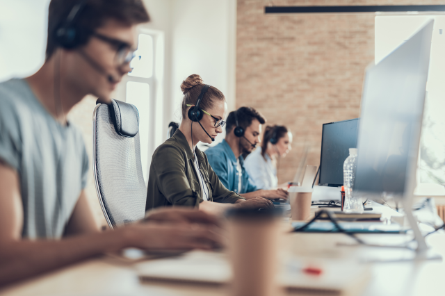 Menschen sitzen im Callcenter. Symbolbild: Internationale Konzerne zieht es nach Portugal: wegen niedriger Löhne, hoher Arbeitslosigkeit und gleichzeitig vielen gut ausgebildeten Arbeitskräfte, die dringend Arbeit suchen. | © Adobe Stock/ Yakobchuk Olena