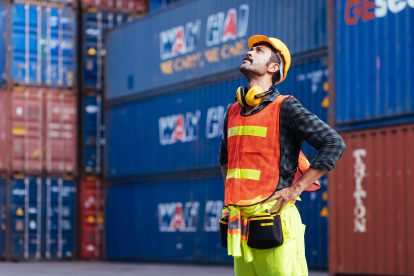 Ein Mann in Schutzweste steht vor Containern.