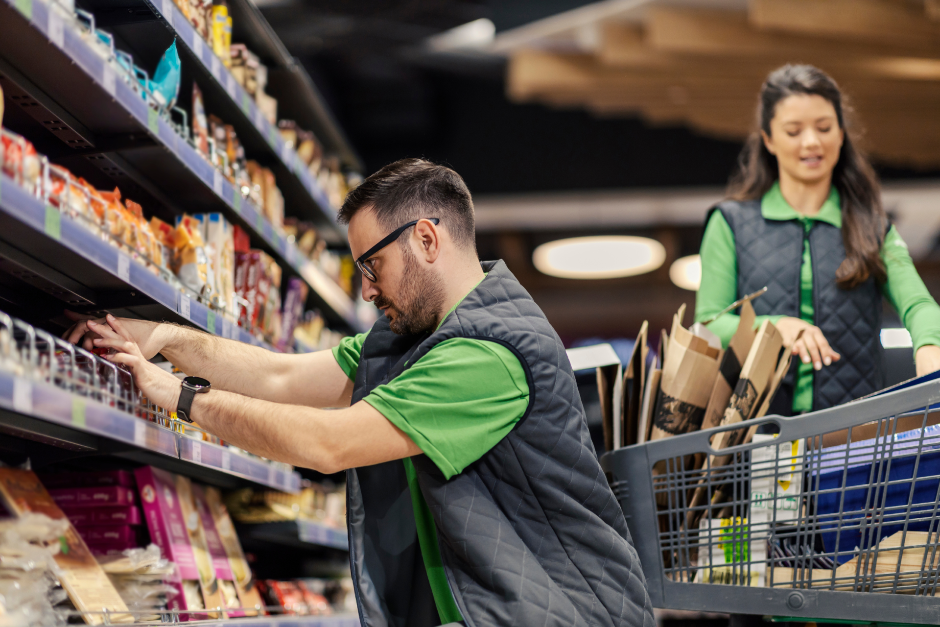 Zwei Mitarbeiter:innen im Supermarkt räumen Regale ein.