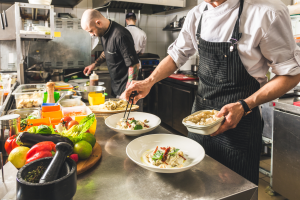 Zwei Köche bereiten Gerichte zu. Symbolbild: Besonders in der Gastronomie werden viele Arbeitskräfte gesucht.