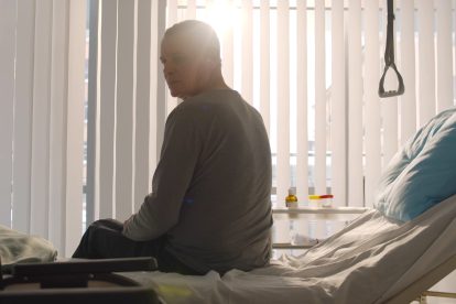 Ein Mann sitzt in einem Krankenbett.