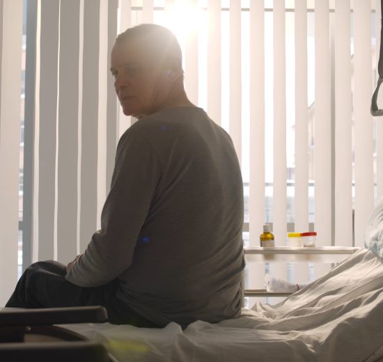 Ein Mann sitzt in einem Krankenbett.