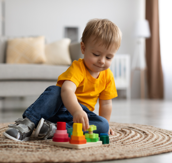Ein Junge im gelben Shirt spielt mit Bauklötzen. Symbolbild für den Konsument:innenschutz, der Spielzeug aus dem Ausland reguliert.