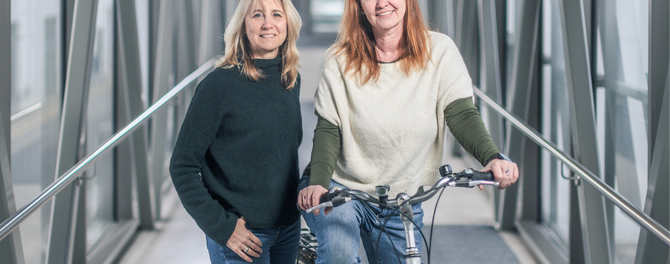 Die Betriebsrätinnen Ursula Sauer und Beatrix Wepner stehen um ein Fahrrad. Sie zeigen, was der Betriebsrat für mehr Klimaschutz tun kann.