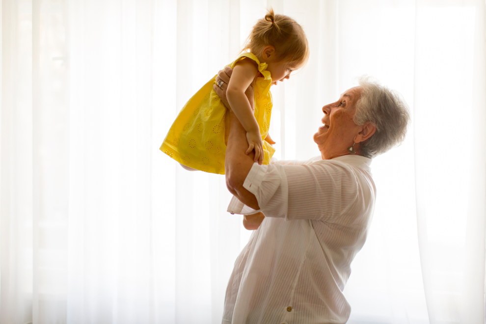 Eine Oma hebt ihre Enkelin in die Luft. Symbolbild: Die Pensionslücke beginnt lange bevor Frauen in den Berufsalltag einsteigen. | © Adobestock/BGStock72