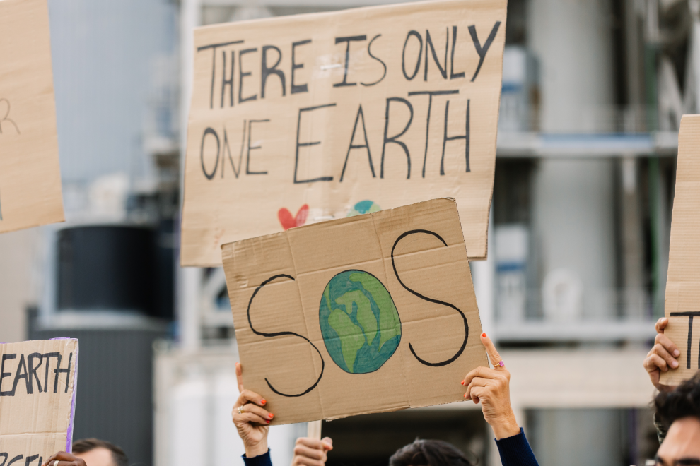 Plakate bei einer Klimademo werden in die Höhe gehalten. Darauf steht SOS und There is no Planet B. Symbolbild: Wie sollen wir heute noch über die Klimakrise sprechen?