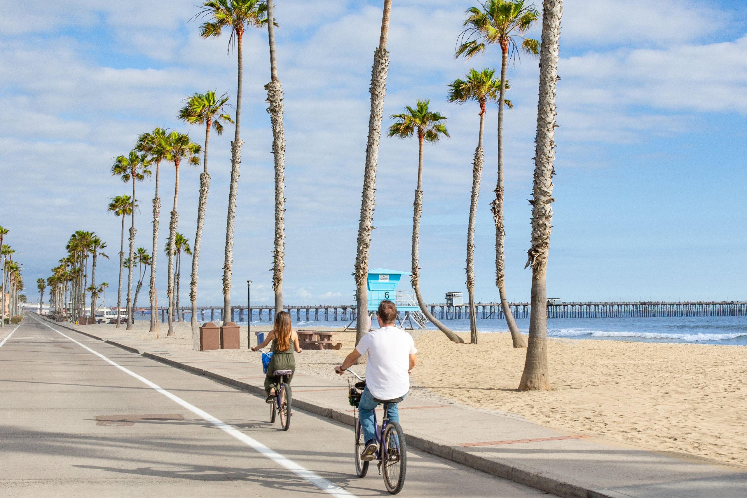 Zwei junge Menschen fahren in Kalifornien am Strand mit dem Fahrrad. Symbolbild: Kalifornien überlegt Superreiche zu besteuern. Doch der Gegenwind ist groß.