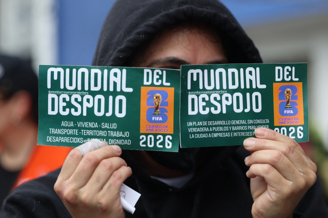 Eine Frau versteckt ihr Gesicht hinter zwei Karten. Symbolbild für die Proteste gegen die Fußball-WM in Mexiko.