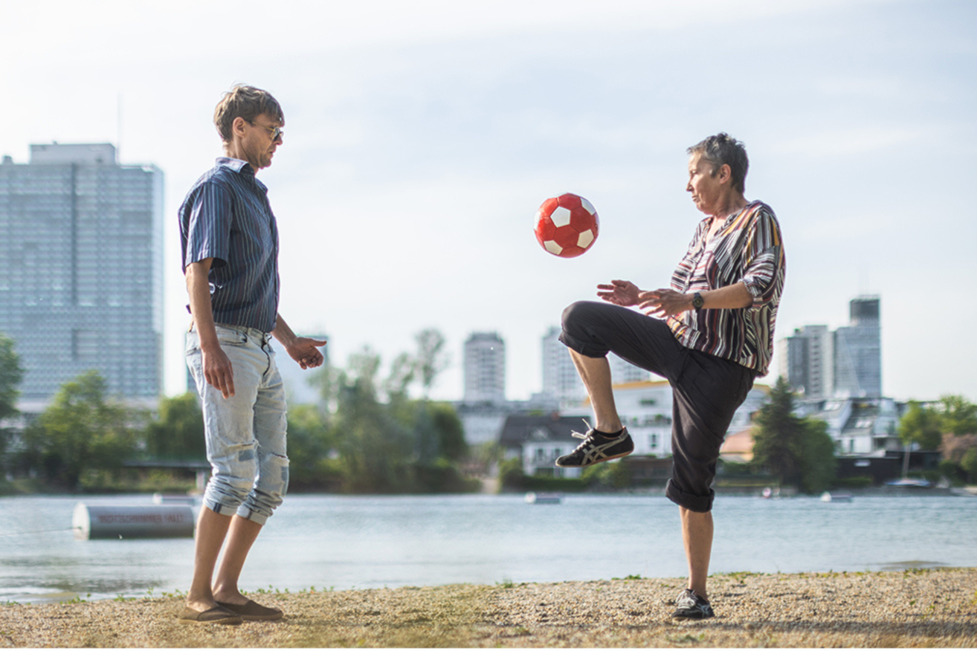 Zwei Menschen spielen vor der Donaukulisse Fußball. „Bitcoinbörserl, Dachgeschoss, vierte Villa, Dividenden, ganze Insel, Yacht im Hafen, schönes Wetter, keine Steuern.“ Songtext der 5/8erl in Ehr’n