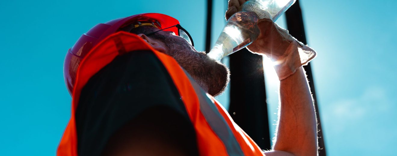 Ein Mann auf einer Baustelle trinkt Wasser. Es ist heiß. Symbbolbild: Klimakrise und Klimaschutzmaßnahmen.