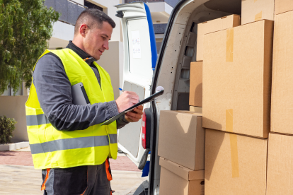 Ein Paketzusteller neben seinem vollgepakten Lieferwagen.