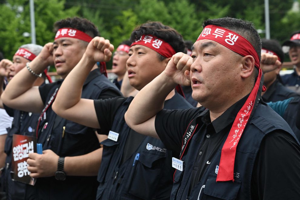 Drei Männer bei einem Streik in Südkorea. Sie halten eine Faust in die Luft. Symbolbild für den Streik gegen Roboter.