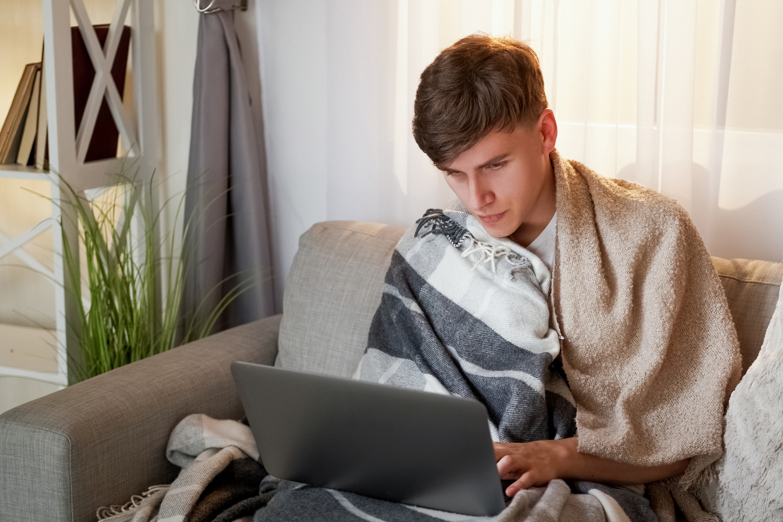 Mann arbeitet krank auf der Couch.